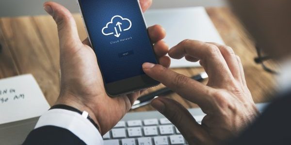 Smartphone utilisé par un homme, sur l'écran un pictogramme parlant d'un système de sauvegarde cloud